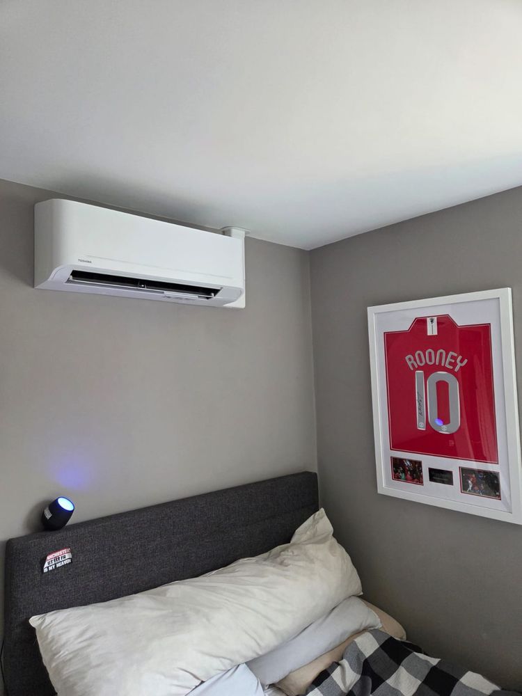 Indoor unit in a bedroom corner, above the bed