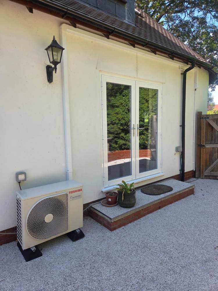 Toshiba outdoor unit on feet beside French doors
