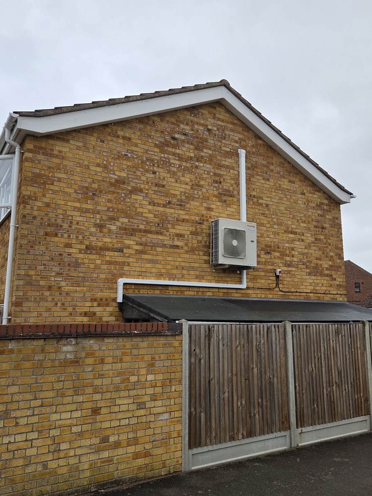 Outdoor unit sited high on a gable end with the pipe run carried straight up