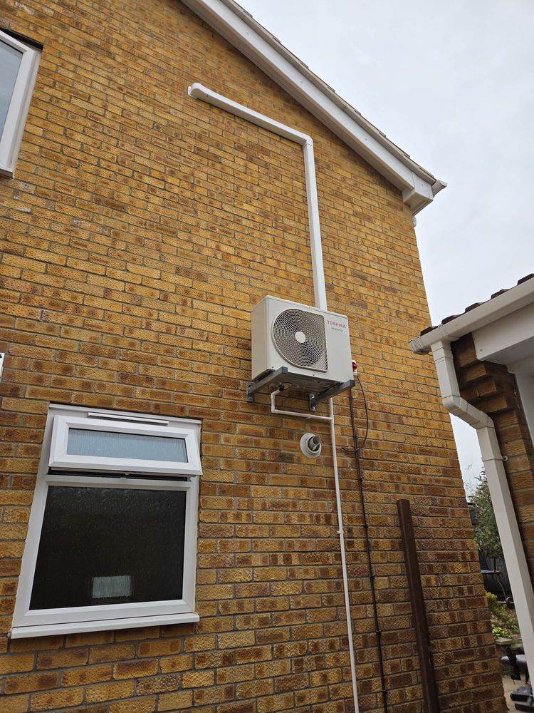 Outdoor unit wall-mounted with the pipe run carried up the brickwork